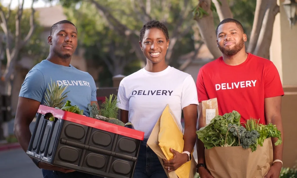 woman and 2 men holding delivery packages