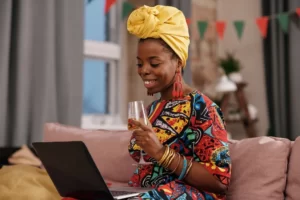 woman looking on her laptop with a glass of wine in hand